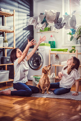 Mother, daughter and dog having fun at laundry room
