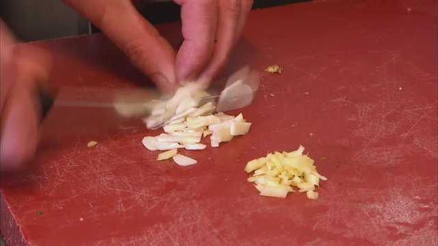 A medium shot of a person chopping garlic