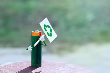Concept humanized figure made of AA battery holds in hands poster with recucle icon. Call for proper disposal. separate garbage collection. single picket. Copy space