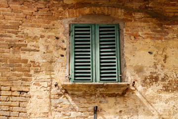 aged green window shutter at grunge brick wall