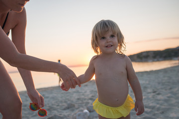 Smiling child girl portrait on sandy beach hold mum to hand