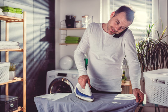 Man talking on phone while ironing clothes