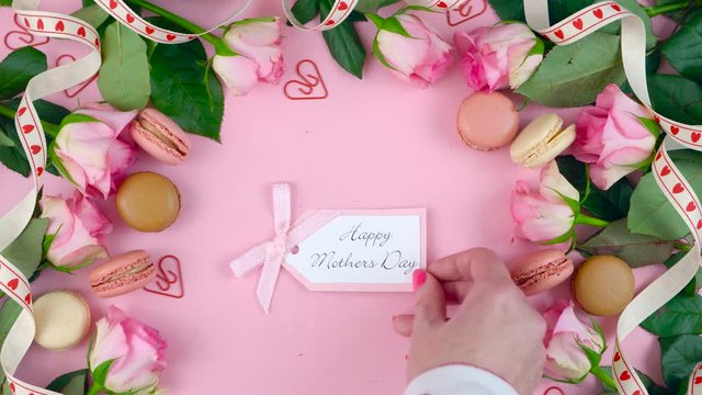 Happy Mother's Day background of pink roses and macaron cookies on pink wood table.