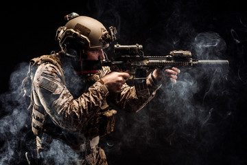 soldier or private military contractor holding rifle. Image on a black background. war, army,...