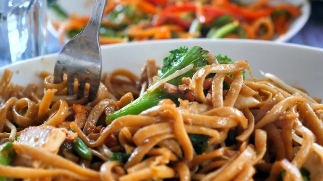 Slow motion (60fps) - Fork spinning and picking up Noodles out of a hot Thai dish. 