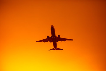 flying airplane silhouette in the orange sky sunset