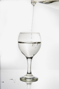 Ett glas i silhuett fylls med p&auml;rlande och friskt vatten