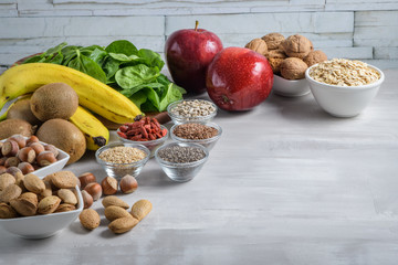 Superfoods on a gray background with copy space. Nuts, beans, greens and seeds. Healthy vegan food.