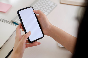 Blank screen mobile phone in female hands on desk