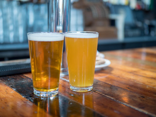 Full pint glasses of ale and golden beers sitting on bar counter top