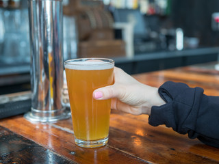 Woman reaching for pint glass of IPA in a bar in a brewery