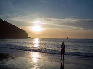 Woman observing the setting sun over the Pacific Ocean