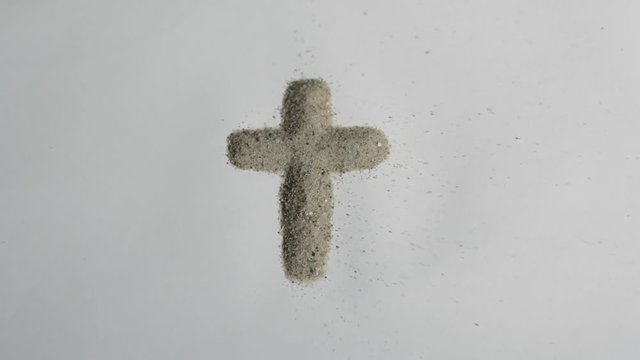 A christian cross made of sand blown away. Footage of objects made out of sand blown away