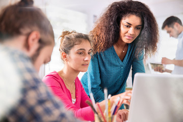 Young colleagues share ideas in front of a laptop