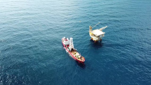 An aerial view from a drone of a soil boring boat (a geotechnical drilling cum analogue survey vessel) close to a oil platform
