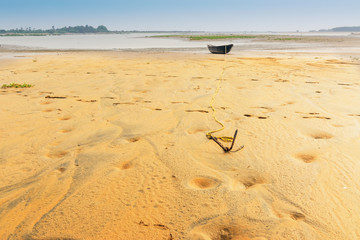 Boat on water tied by a rope with an anchor on river bed.