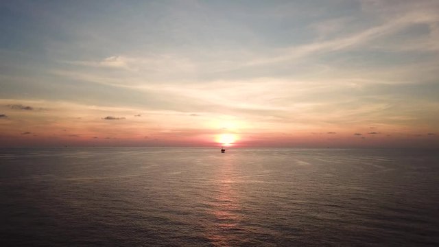 Aerial view from a drone of a small offshore platform in the middle of the ocean during sunset
