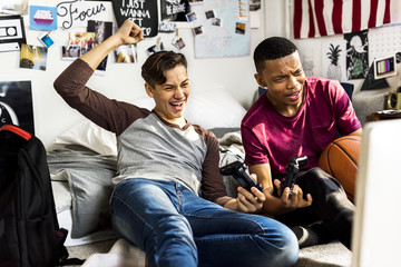 Teenage boys hanging out in a bedroom playing video games together © Rawpixel.com
