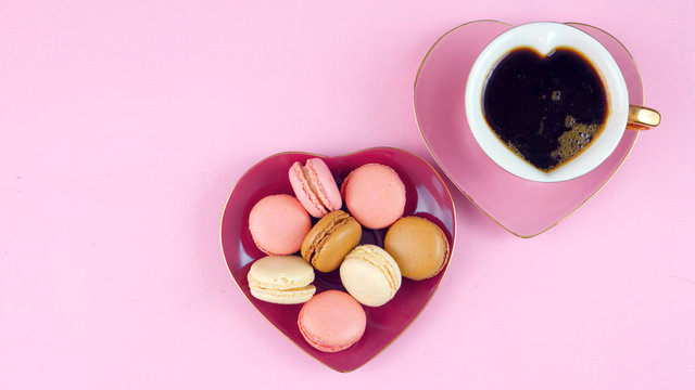 Serving Mother's Day coffee and macarons with copy space overhead on pink wood table background.