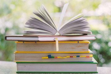 Stack of book on blurred natural green background