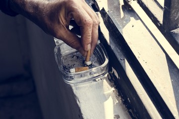 Closeup of hand smoking cigarette with ashtray