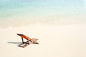 Fototapeta na wymiar One empty chair on white sandy beach near the sea