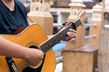 Fototapeta premium Man playing acoustic guitar with a capo clip