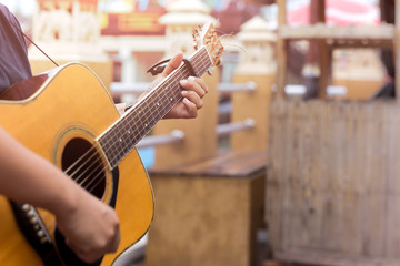 Man playing acoustic guitar with a capo clip