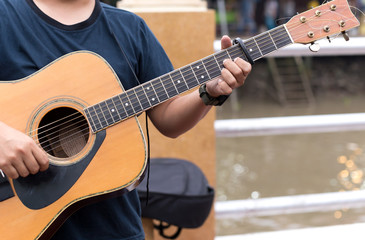 Fototapeta premium Man playing acoustic guitar with a capo clip