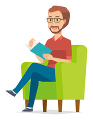 A bearded man wearing eyeglasses is reading on a sofa