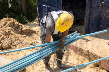 Worker picking up blue water pipe on construction site
