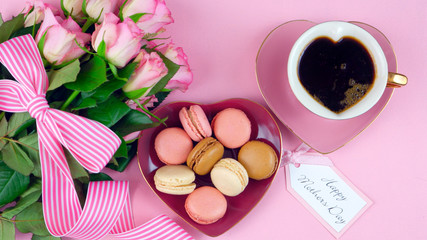 Obraz na płótnie Canvas Serving Mother's Day coffee and macarons with roses gift overhead on pink wood table background.