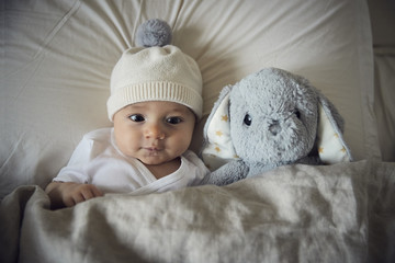 High angle view of baby boy with teddy bear lying on bed at home