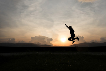 Silhouette of happy man jumping at sunset