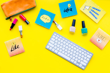 Beauty blogging concept. Work desk with keyboard, cosmetics and social media icons on yellow desk top view