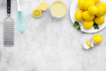 Cook lemon curd. Sweet cream in bowl, fruits, kitchen utensils on grey background top view copy space