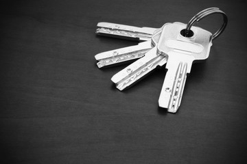 Bunch of silver coloured keys on dark table, concept for real estate or renting home with copy space
