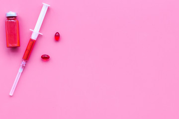 Medical therapy. Syringe, bottle with drug, pills on pink background top view copy space