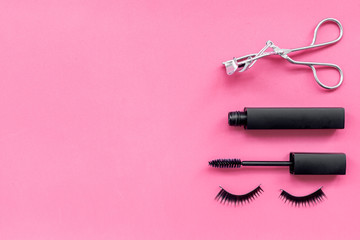 Makeup set for expressive eyelashes. Mascara, false eyelashes, eyelash curler on pink background top view space for text