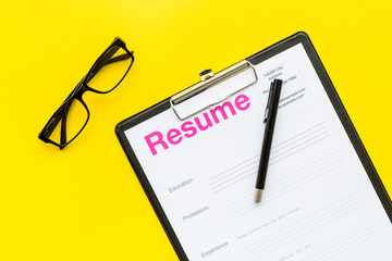 Looking for work concept. Resume on pad near pen and glasses on yellow background top view