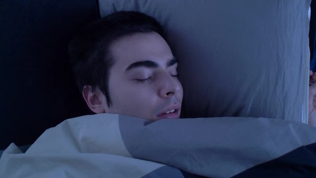 Young man in bed sleeping and snoring