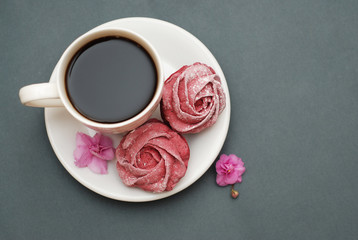 Sweet Pink Meringues and Cup of Coffee on Blue Gray background with Pink Flowers. Spring Background with copy space. Breakfast.