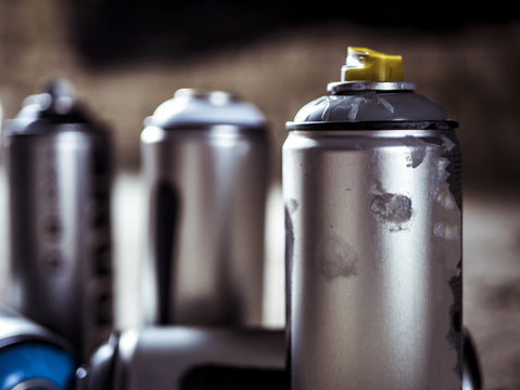 close macro shot of spray paint cans droped on the dusty ground