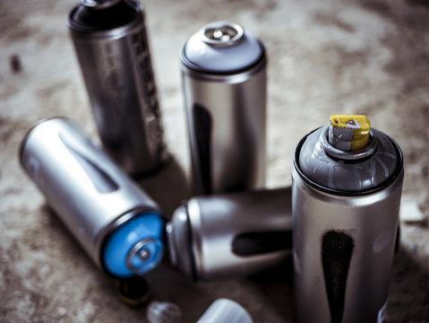 close macro shot of spray paint cans droped on the dusty ground