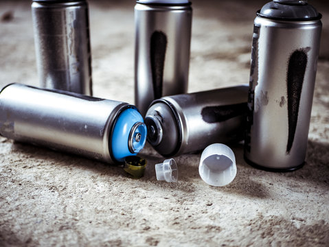 close macro shot of spray paint cans droped on the dusty ground