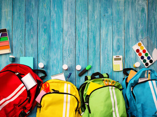 Fototapeta Colourful children schoolbags on wooden floor. Backpacks with school accessories obraz