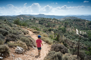 Fototapeta premium Boy hiking on path amidst field, Crete, Greece