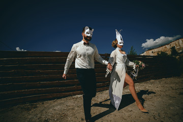 bearded groom and beautiful bride posing in rabbit masks