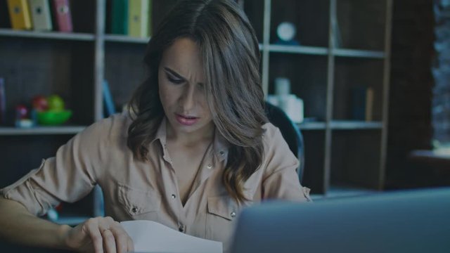 Upset business woman working on laptop in office. Portrait of unhappy woman working with documents. Close up of worried businesswoman face looking monitor. DIssapointed manager working with papers