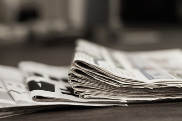 Pile of fresh morning newspapers on the table at office. Latest financial and business news in...